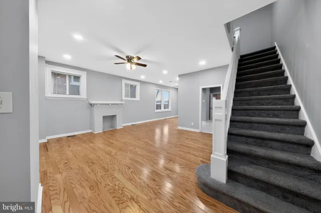 a view of an empty room with wooden floor and stairs