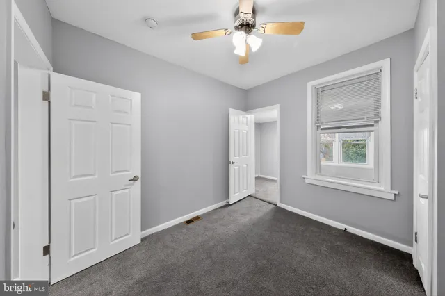 an empty room with windows and fan