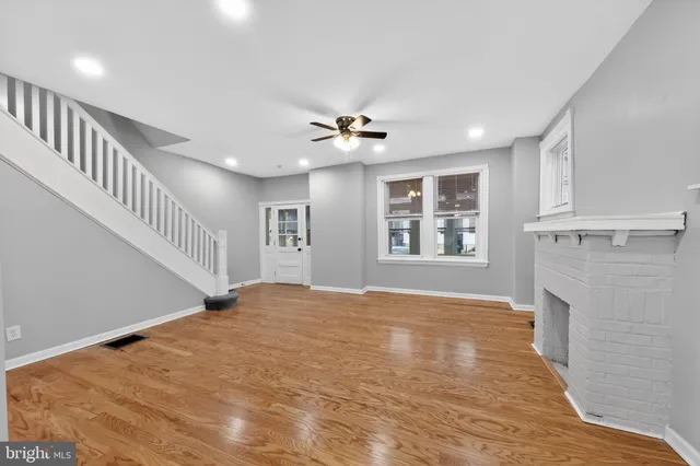 a view of an empty room with window and wooden floor