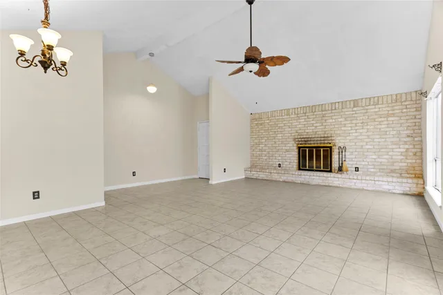 an empty room with a chandelier fan and windows
