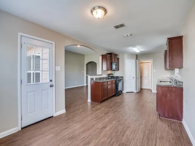 a large kitchen with cabinets wooden floor and stainless steel appliances