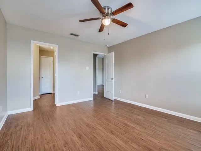 an empty room with wooden floor and a ceiling fan