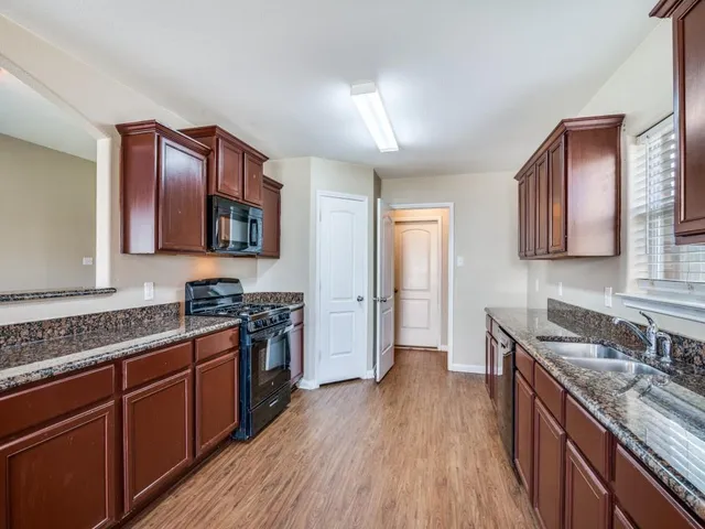 a kitchen with stainless steel appliances granite countertop wooden cabinets a stove top oven a sink and dishwasher