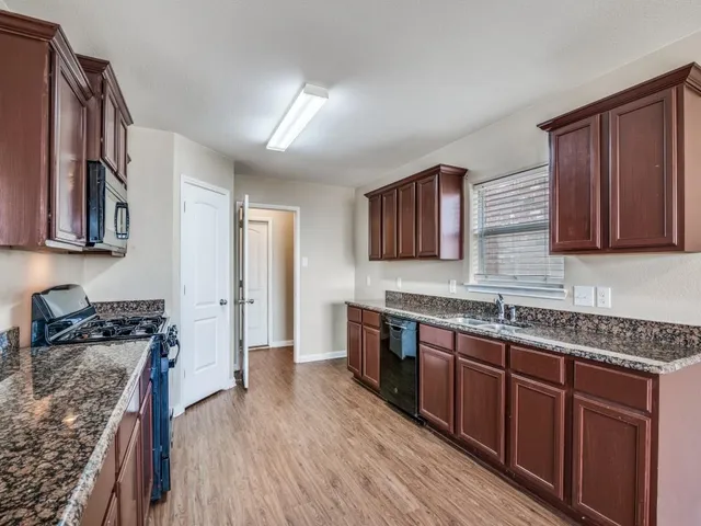 a kitchen with stainless steel appliances granite countertop wooden cabinets a stove top oven a sink and dishwasher