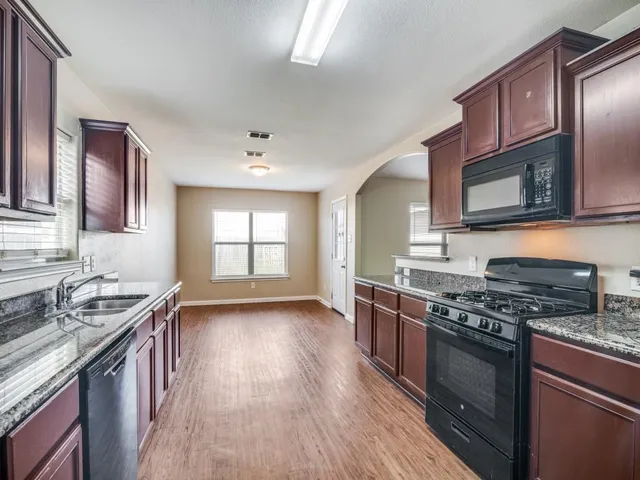 a kitchen with stainless steel appliances granite countertop wooden cabinets stove top oven and sink