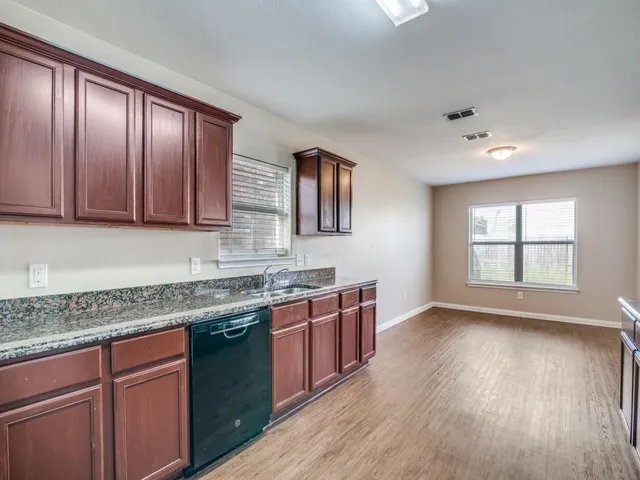 a kitchen with stainless steel appliances granite countertop wooden floors and wooden cabinets