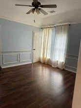 an empty room with wooden floor fan and windows