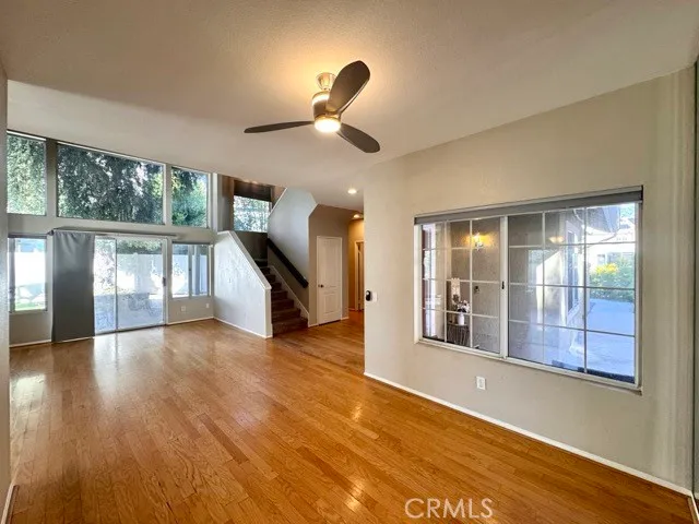 a view of an empty room with wooden floor fireplace and a window