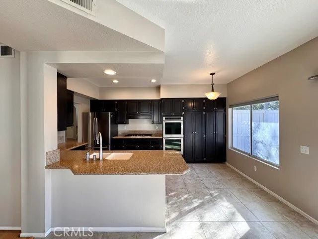 a large kitchen with stainless steel appliances granite countertop a stove refrigerator and cabinets