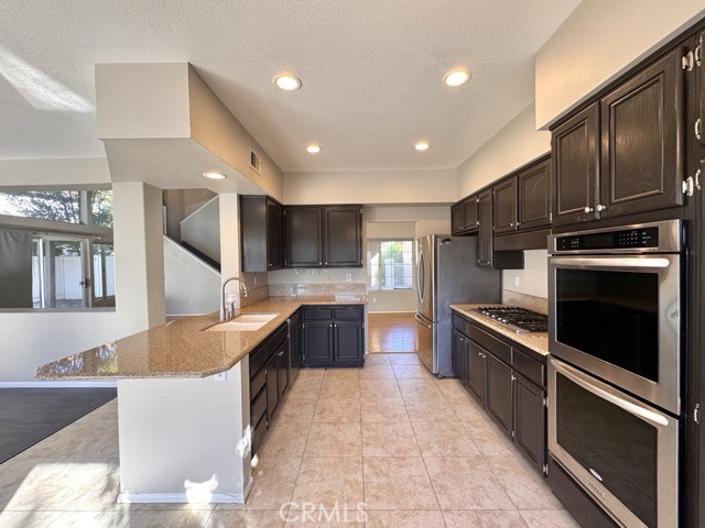 40085 Temecky Way Murrieta, CA 92562 - Photo 17 of 55 a large kitchen with stainless steel appliances granite countertop a stove refrigerator and cabinets