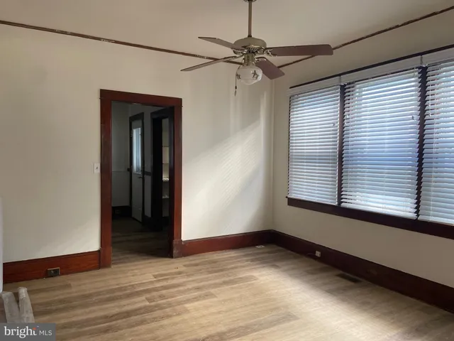 an empty room with wooden floor fan and windows