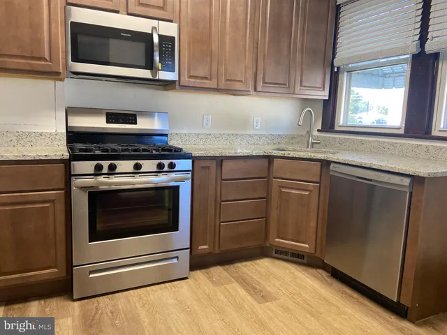a kitchen with granite countertop a stove top oven microwave and cabinets