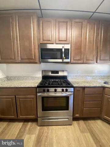 a kitchen with granite countertop cabinets stainless steel appliances and wooden floor