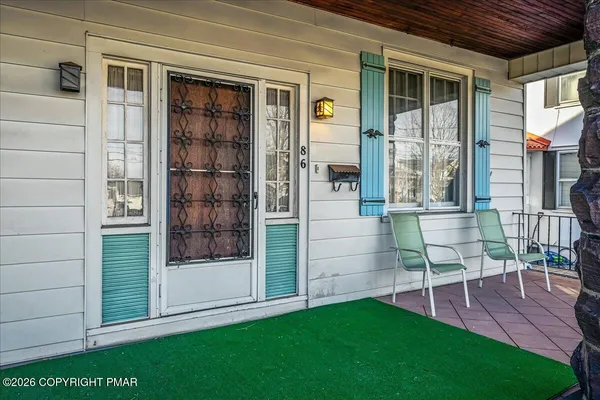 a view of front door of house with outdoor seating and a window