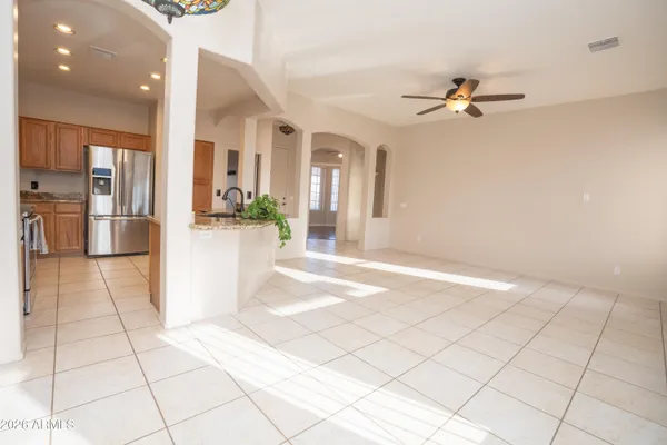 an empty room with wooden floor chandelier fan and windows