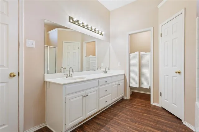 a spacious bathroom with double vanity a mirror and a shower