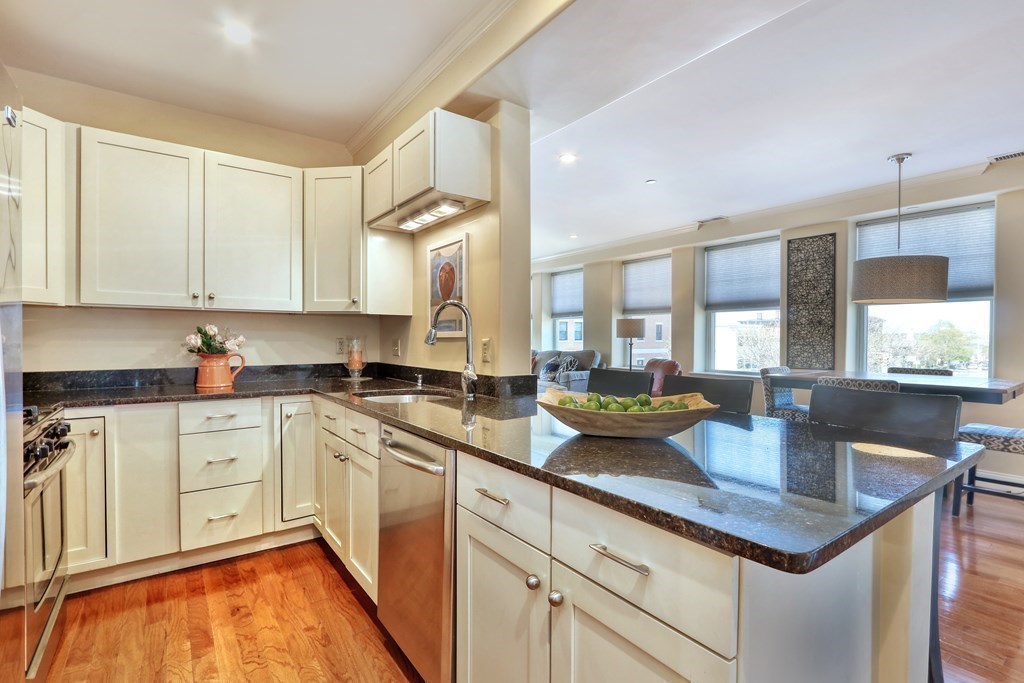 426 Main Street, Unit 402 Melrose, MA 02176 - Photo 5 of 24 a kitchen with stainless steel appliances granite countertop a sink dishwasher and white cabinets with wooden floor