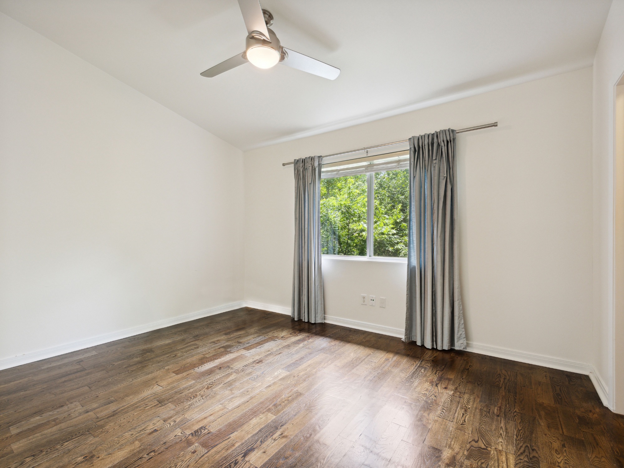 1503 West 9th Street, Unit 204 Austin, TX 78703 - Photo 11 of 21 Room featuring wood-finish flooring, a ceiling fan with integrated lighting, and a window providing natural light