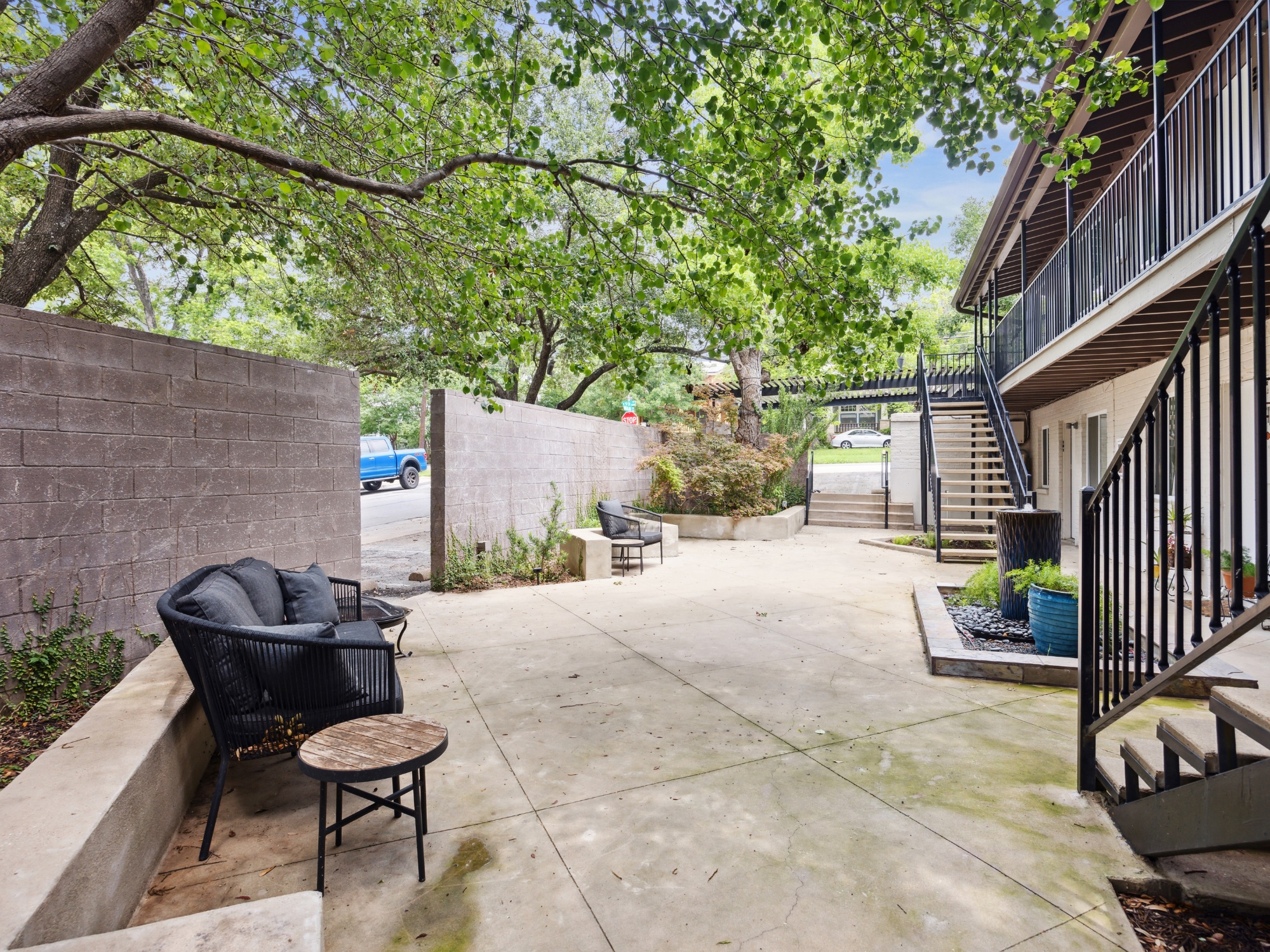1503 West 9th Street, Unit 204 Austin, TX 78703 - Photo 16 of 21 Expansive concrete patio area with a privacy wall, surrounded by mature trees