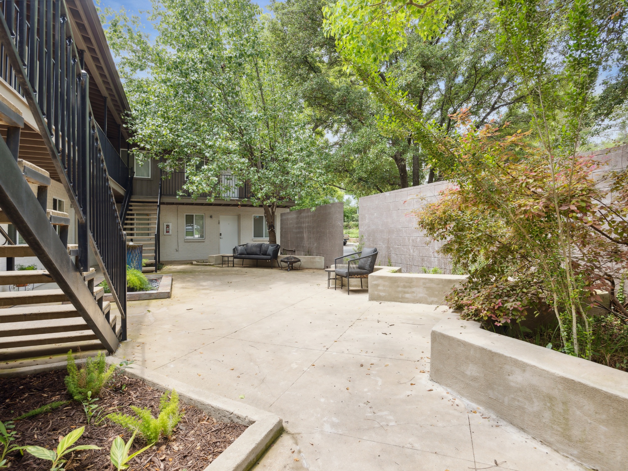 1503 West 9th Street, Unit 204 Austin, TX 78703 - Photo 4 of 21 Concrete courtyard featuring built-in planters and mature trees