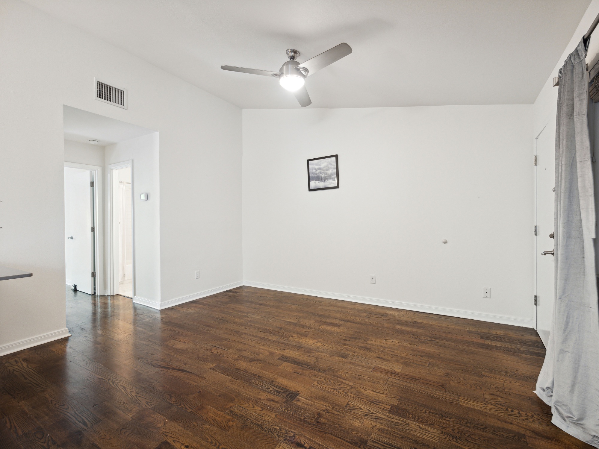 1503 West 9th Street, Unit 204 Austin, TX 78703 - Photo 5 of 21 Expansive living area featuring rich wood-finish flooring, a modern ceiling fan, and crisp white walls