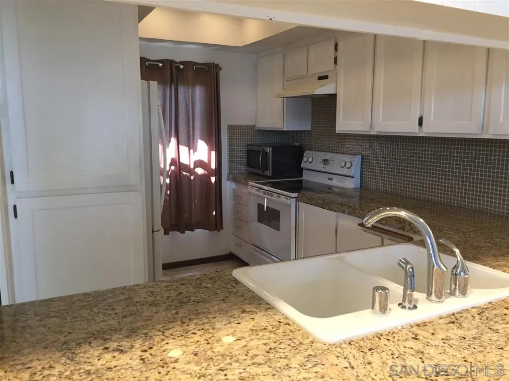 1939 Alga Road, Unit A Carlsbad, CA 92009 - Photo 14 of 25 a kitchen with stainless steel appliances granite countertop a sink a stove and a refrigerator