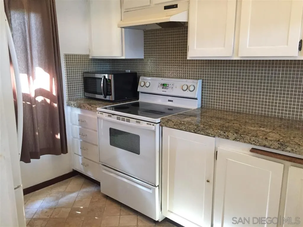 1939 Alga Road, Unit A Carlsbad, CA 92009 - Photo 15 of 25 a kitchen with granite countertop white cabinets and white appliances