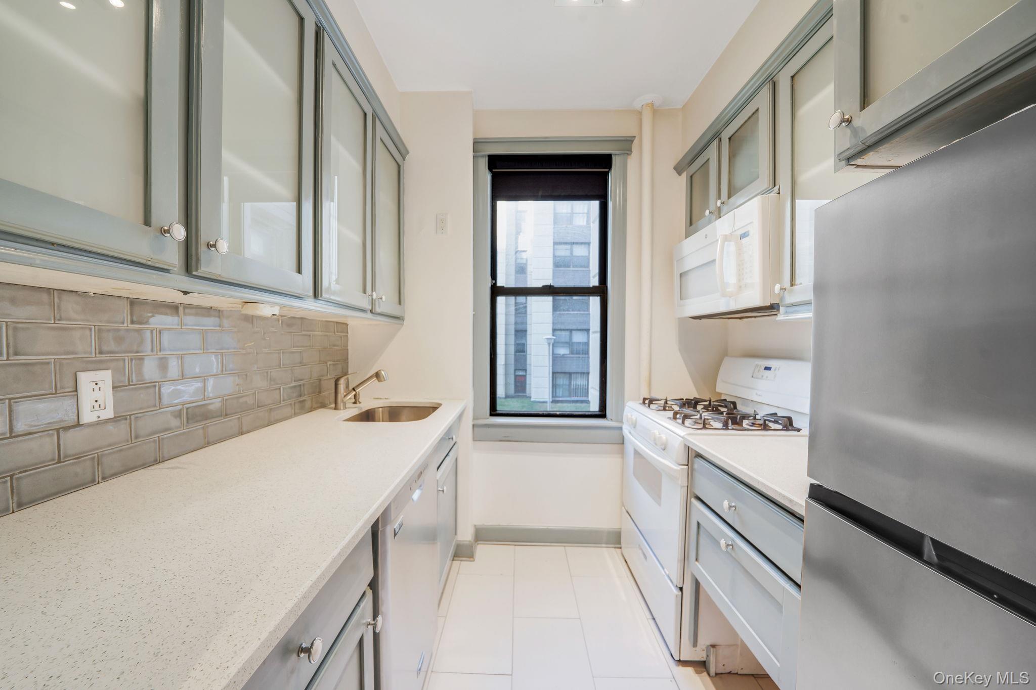 98-33 64th Avenue, Unit 1D Queens, NY 11374 - Photo 13 of 20 a kitchen with a sink a stove and cabinets