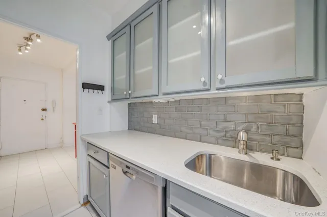 a close view of a sink and cabinets in a white kitchen