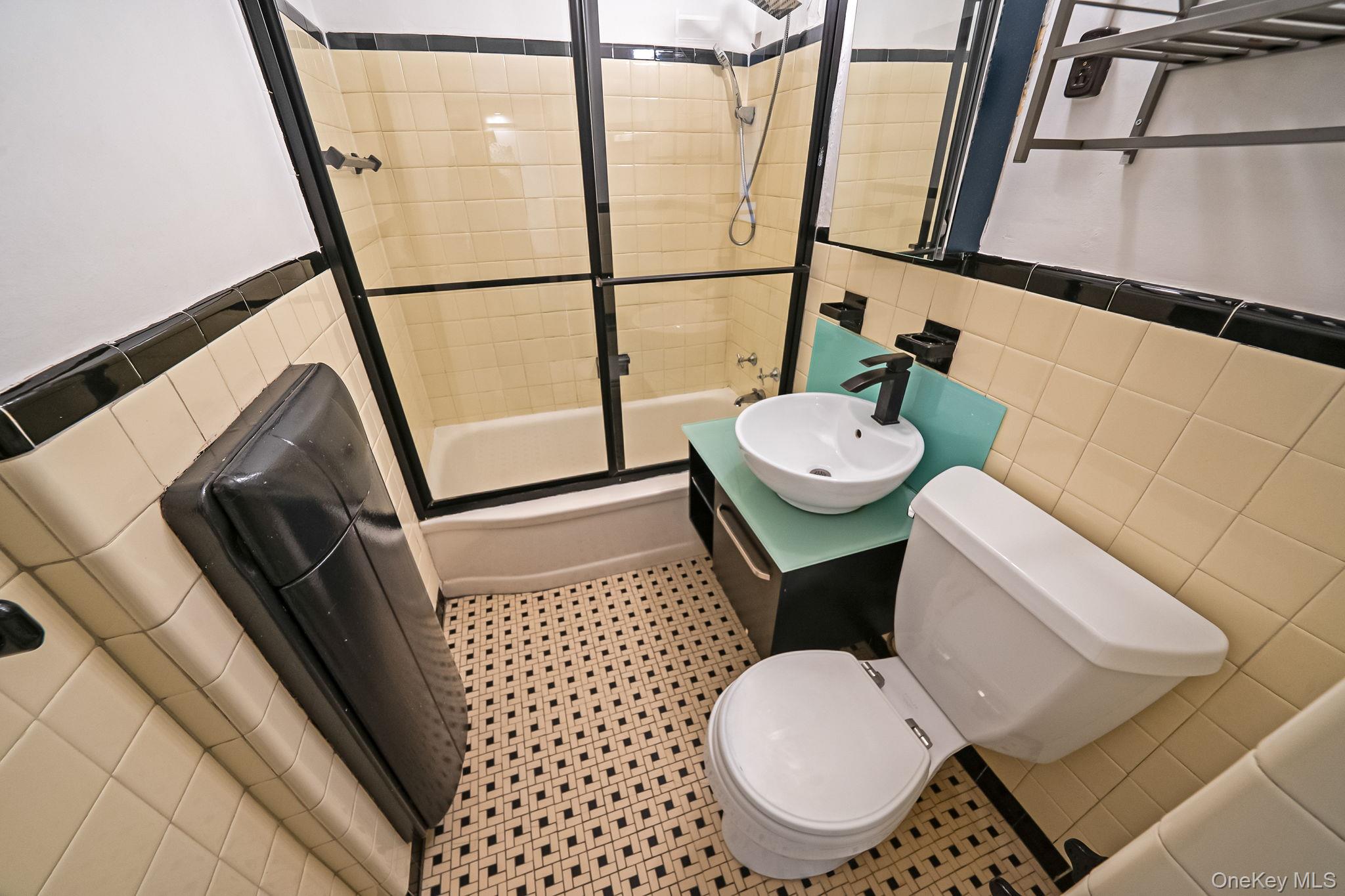 98-33 64th Avenue, Unit 1D Queens, NY 11374 - Photo 19 of 20 a bathroom with a sink a toilet a mirror and shower