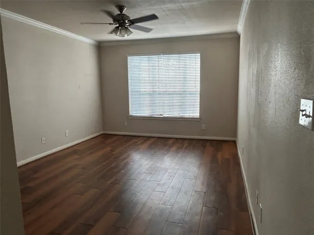 an empty room with wooden floor windows and fan