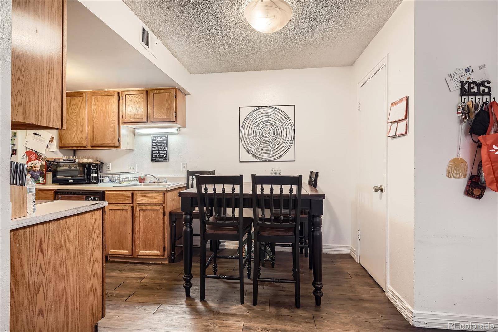 1358 South Irving Street, Unit 53 Denver, CO 80219 - Photo 9 of 28 a kitchen with a table chairs refrigerator and cabinets