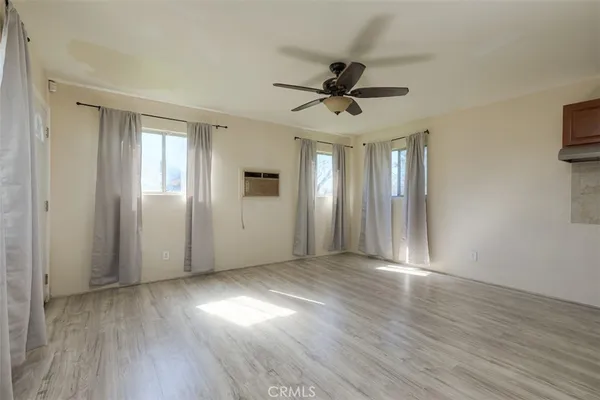 an empty room with wooden floor fan and windows