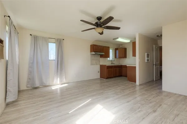 a view of a livingroom with a ceiling fan a kitchen space with wooden floor and a ceiling fan