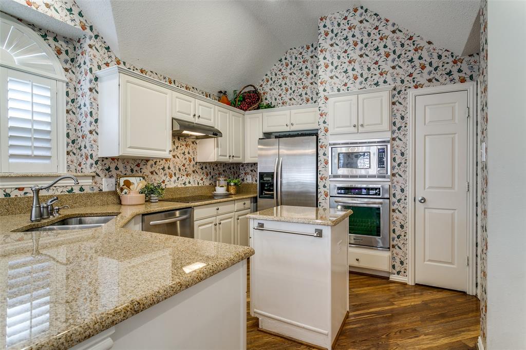 14596 Blueberry Court Addison, TX 75001 - Photo 11 of 32 Kitchen with a center island, stainless steel appliances, wallpapered walls, and white cabinetry