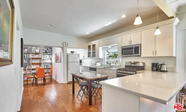 a kitchen with stainless steel appliances granite countertop a sink cabinets and wooden floor