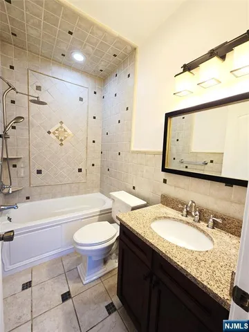 a bathroom with a granite countertop sink a toilet a mirror and bathtub
