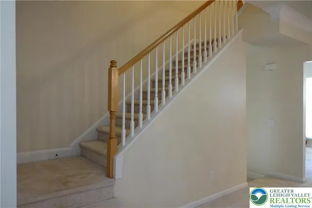 a view of staircase with railing and white walls