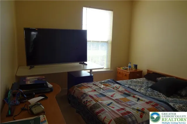 a bedroom with a bed and a flat tv screen on dresser