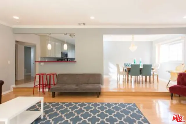 a living room with furniture and a dining table with wooden floor