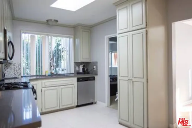 a kitchen with white cabinets and a window
