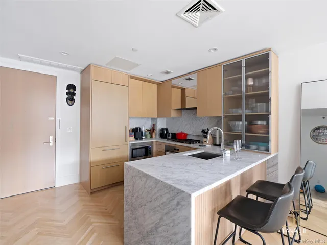 a kitchen with a refrigerator a stove a sink and a dining table with wooden floor