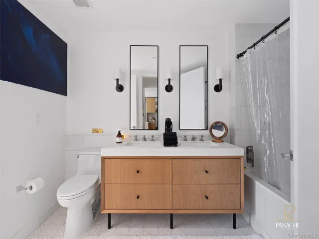 a bathroom with a double vanity sink toilet mirror and shower