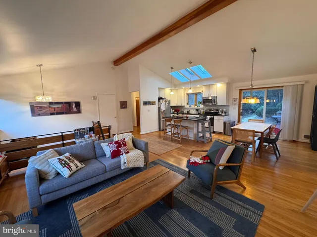 a living room with furniture a dining table with rug floor and a chandelier