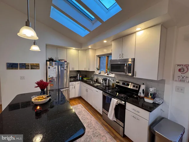 a kitchen with stainless steel appliances granite countertop a sink a stove and a refrigerator