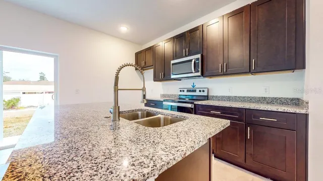 a kitchen with kitchen island granite countertop a sink stove and cabinets