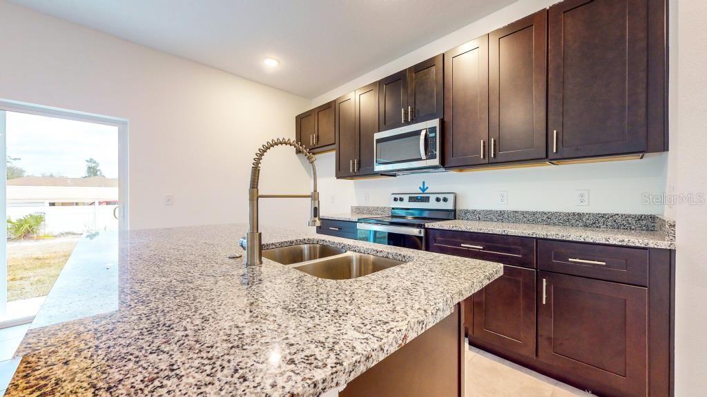 9809 North Swanee Terrace Dunnellon, FL 34433 - Photo 8 of 24 a kitchen with kitchen island granite countertop a sink stove and cabinets