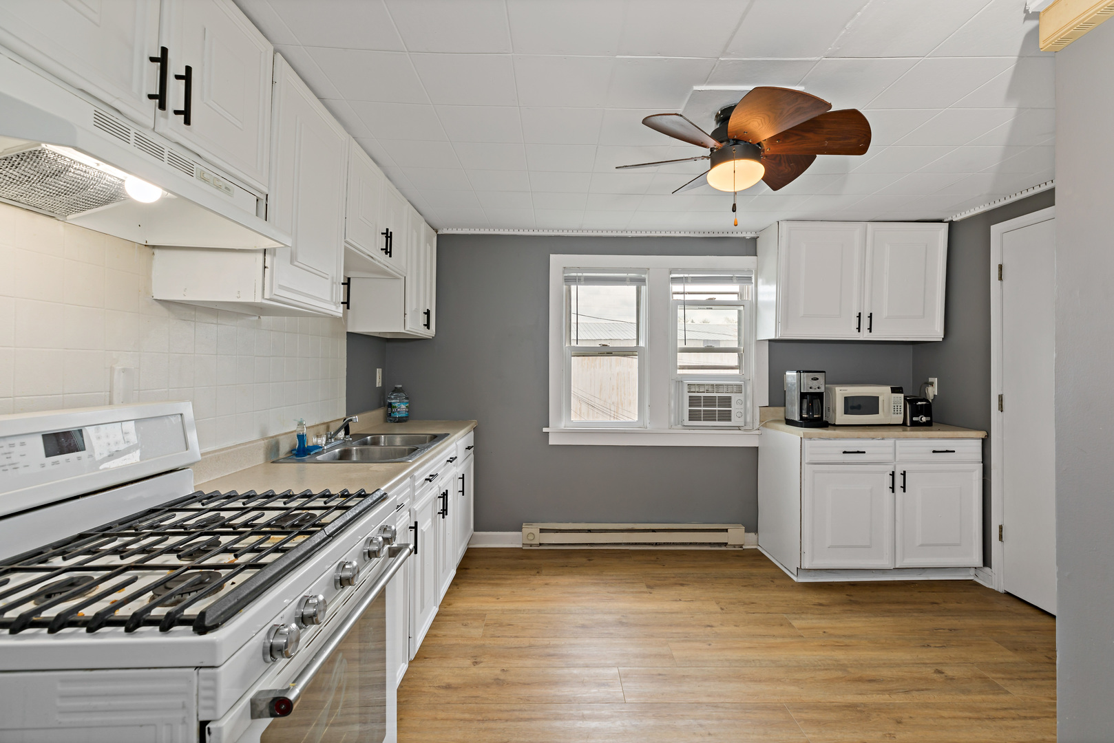 3441 Chicago Road Steger, IL 60475 - Photo 15 of 28 a kitchen with stainless steel appliances granite countertop a stove a sink and white cabinets with wooden floor
