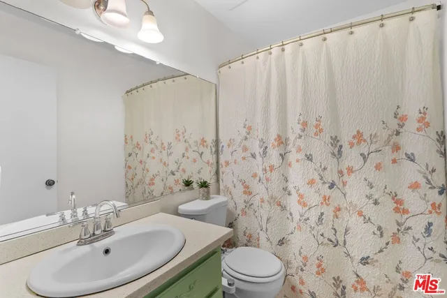 a bathroom with a sink a toilet and shower curtain
