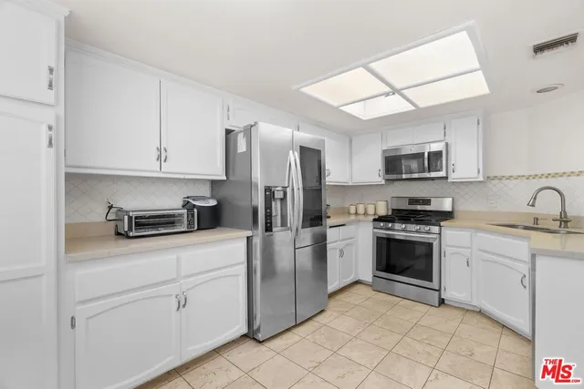 a kitchen with cabinets stainless steel appliances and a counter space